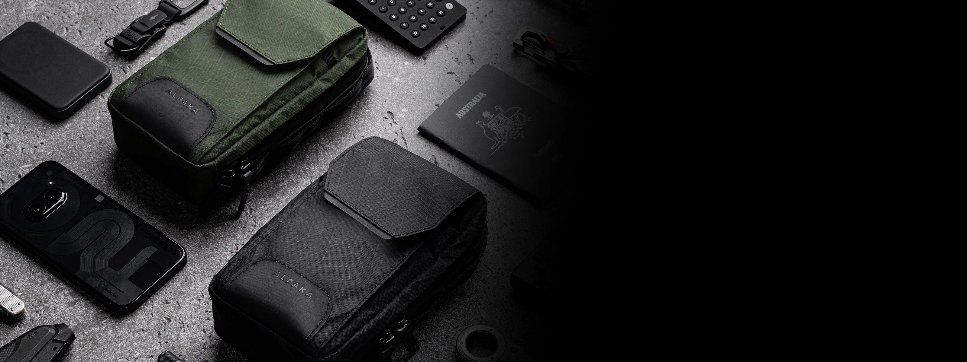 Dos organizadores Alpaka Gear en negro y verde, rodeados de accesorios EDC sobre una superficie de hormigón