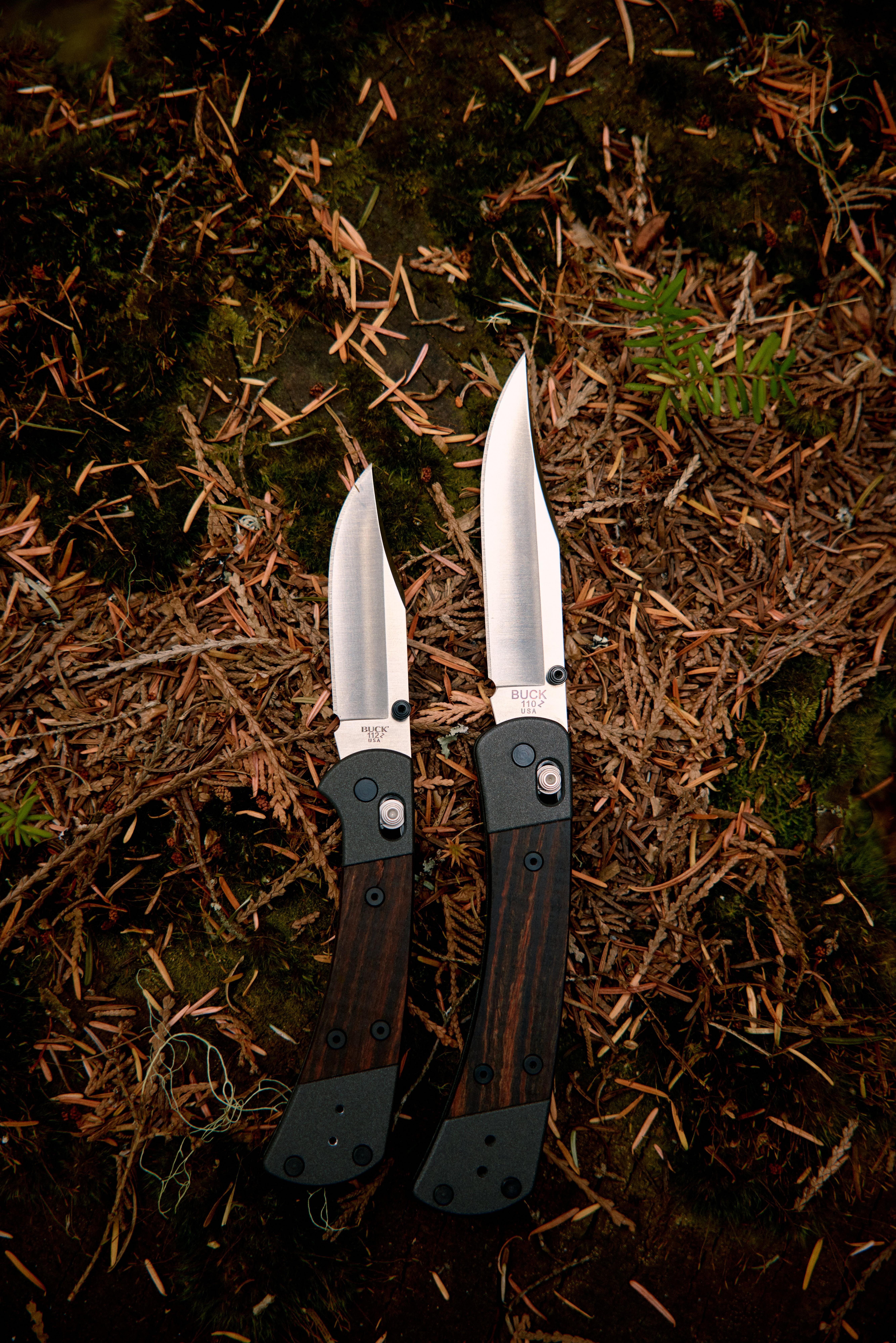 Buck 110 en 112 Crossbar Lock opengeklapt naast elkaar op de bosbodem