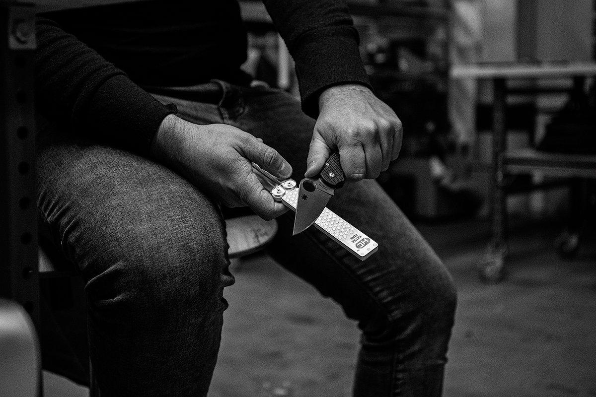 Une personne en train d'aiguiser un couteau avec une pierre à aiguiser DMT Diafold