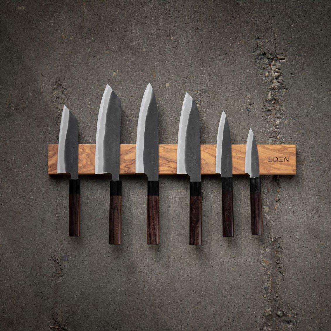 Two Eden Kanso Aogami kitchen knives on a wooden cutting board, surrounded by fresh ingredients.