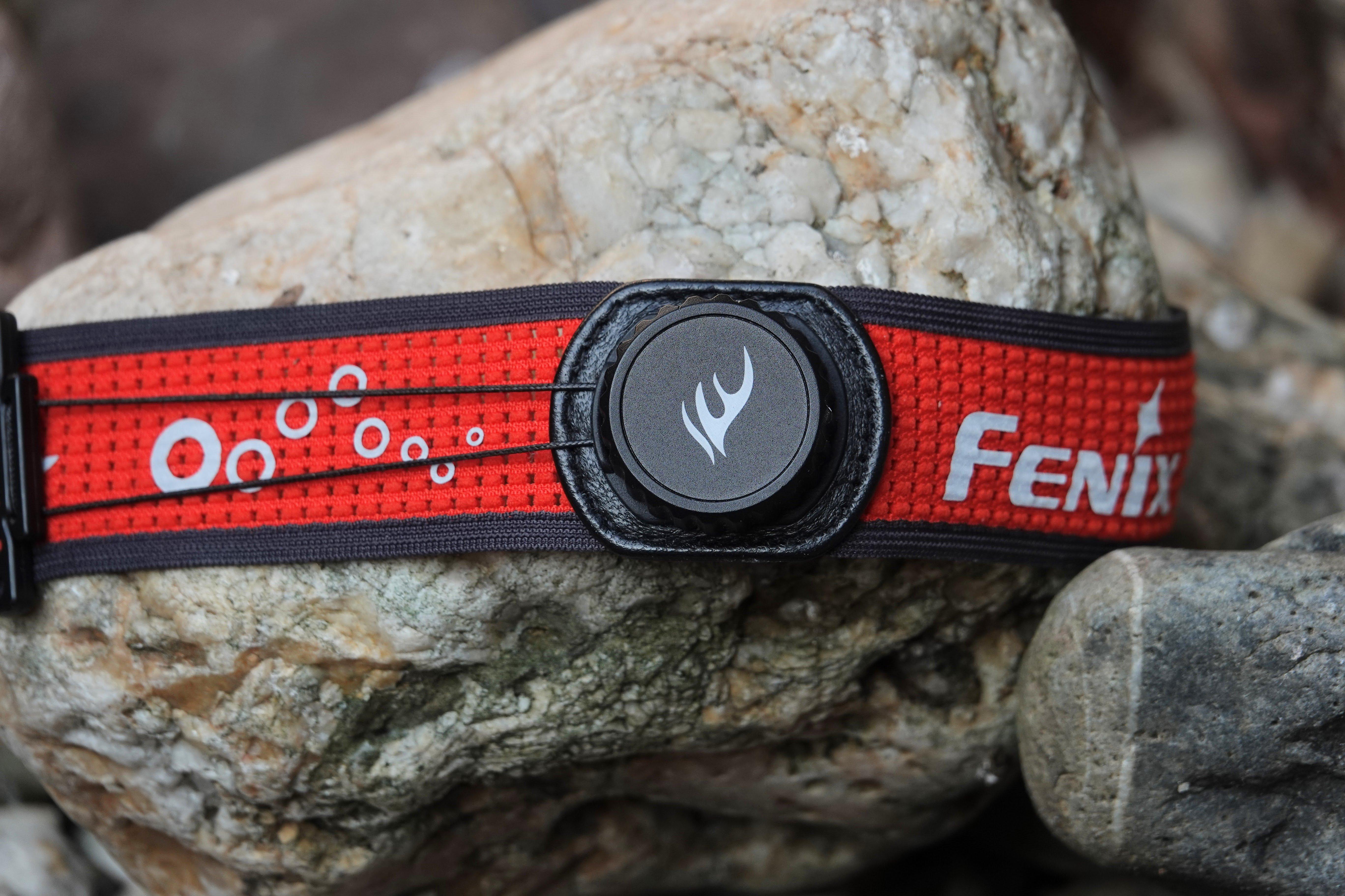 Rode band van de Fenix HM65R-T V2.0-zaklamp rond een steen