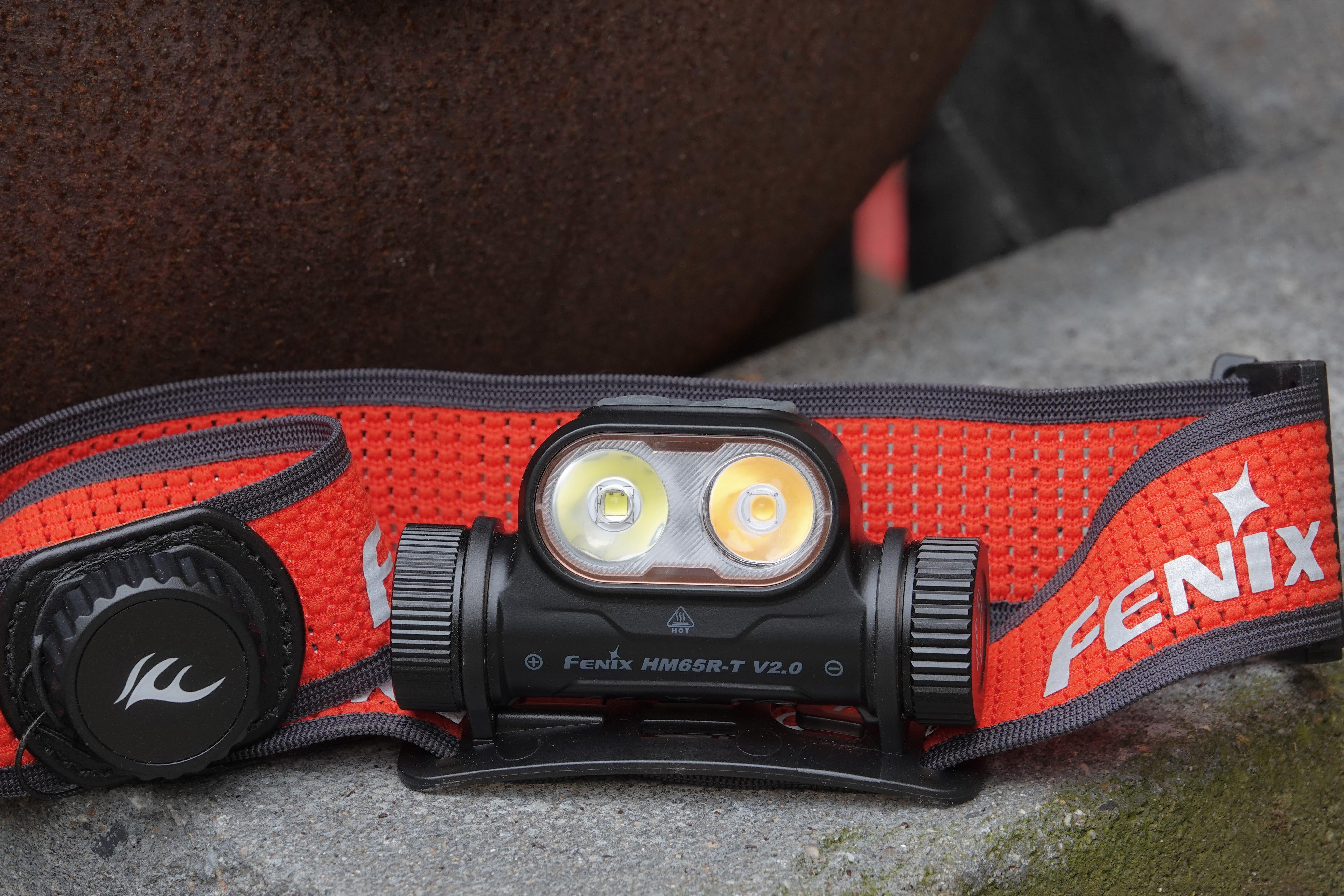 De Fenix HM65R-T V2.0 zwarte hoofdlamp met rode nekband op de betonnen vloer