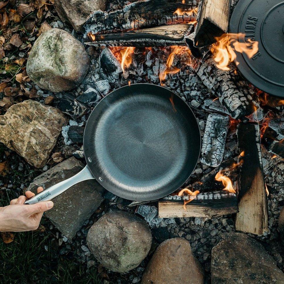 Een Skottsberg koekenpan en gietijzeren pan direct op de kolen van een kampvuur