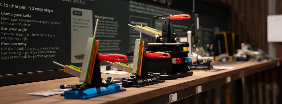 Verschiedene Schleifsysteme stehen nebeneinander auf einer Oberfläche aus Holz im Knivesandtools Experience Center.