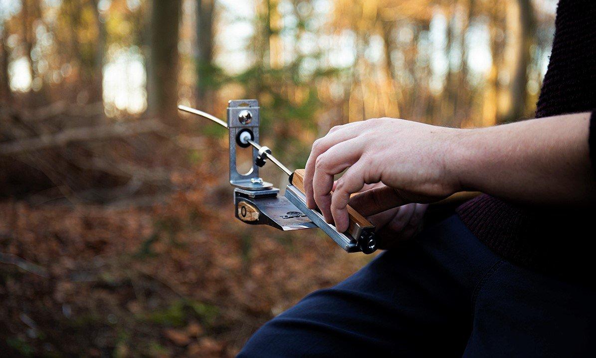 Una persona sta affilando un'ascia nella foresta con l'affilacoltelli KME Sharpeners