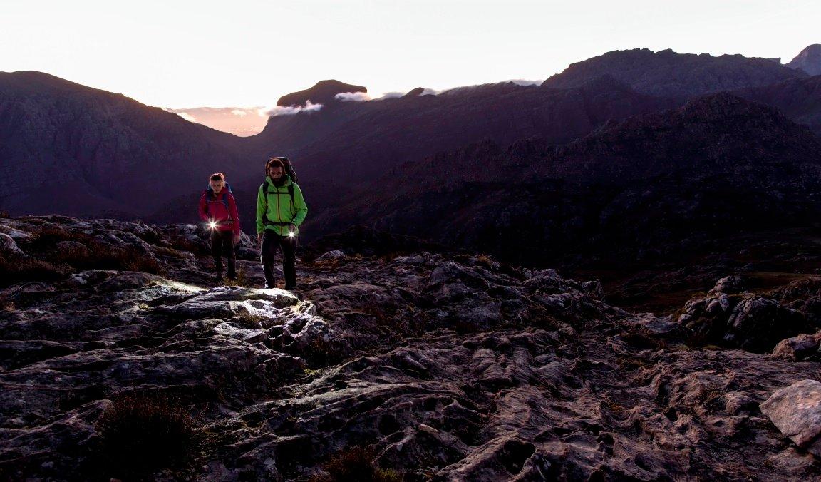 Dos personas andando por la montaña con linternas Ledlenser