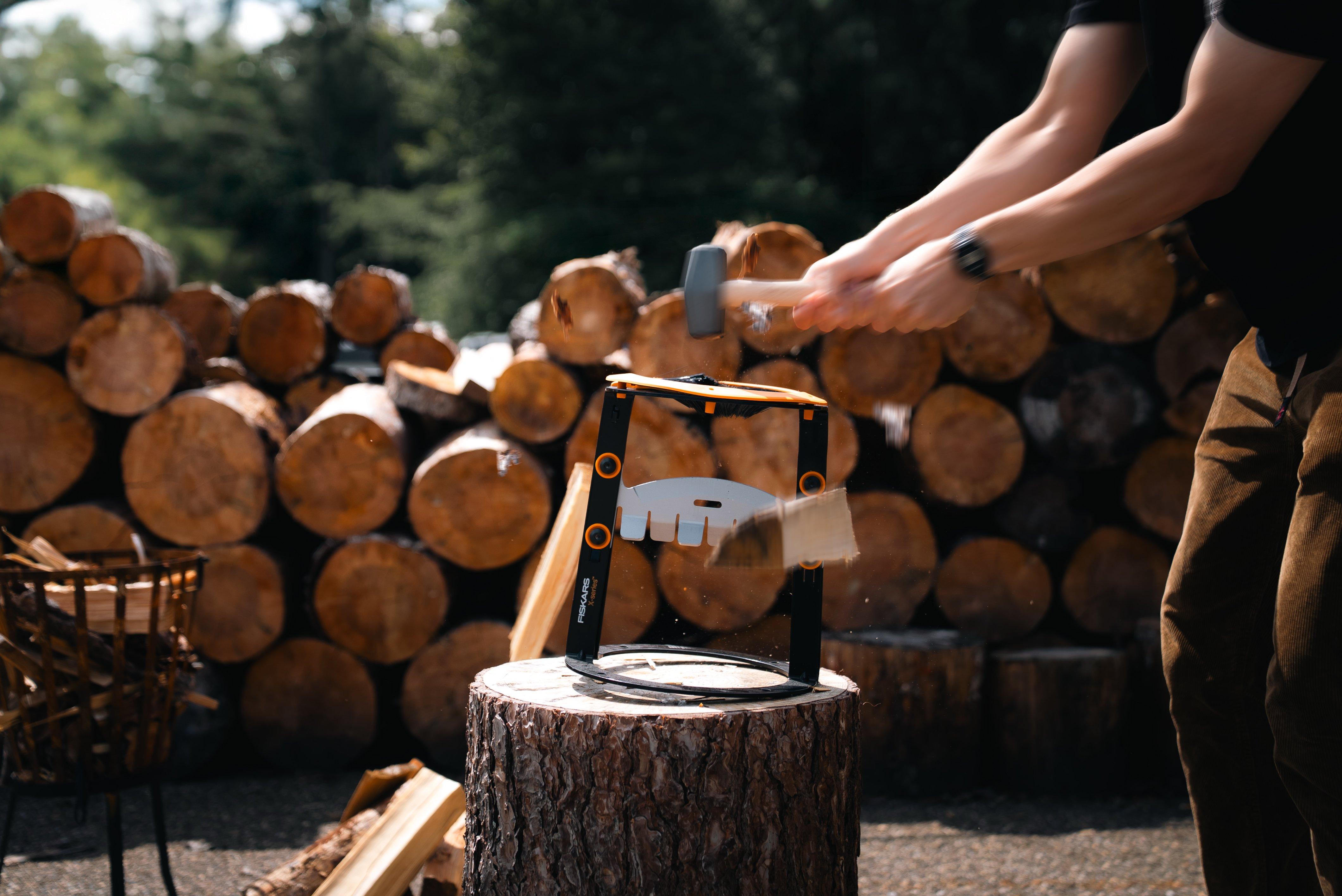 Person, die draußen mit einem Anzündholzspalter ein Holzstück spaltet