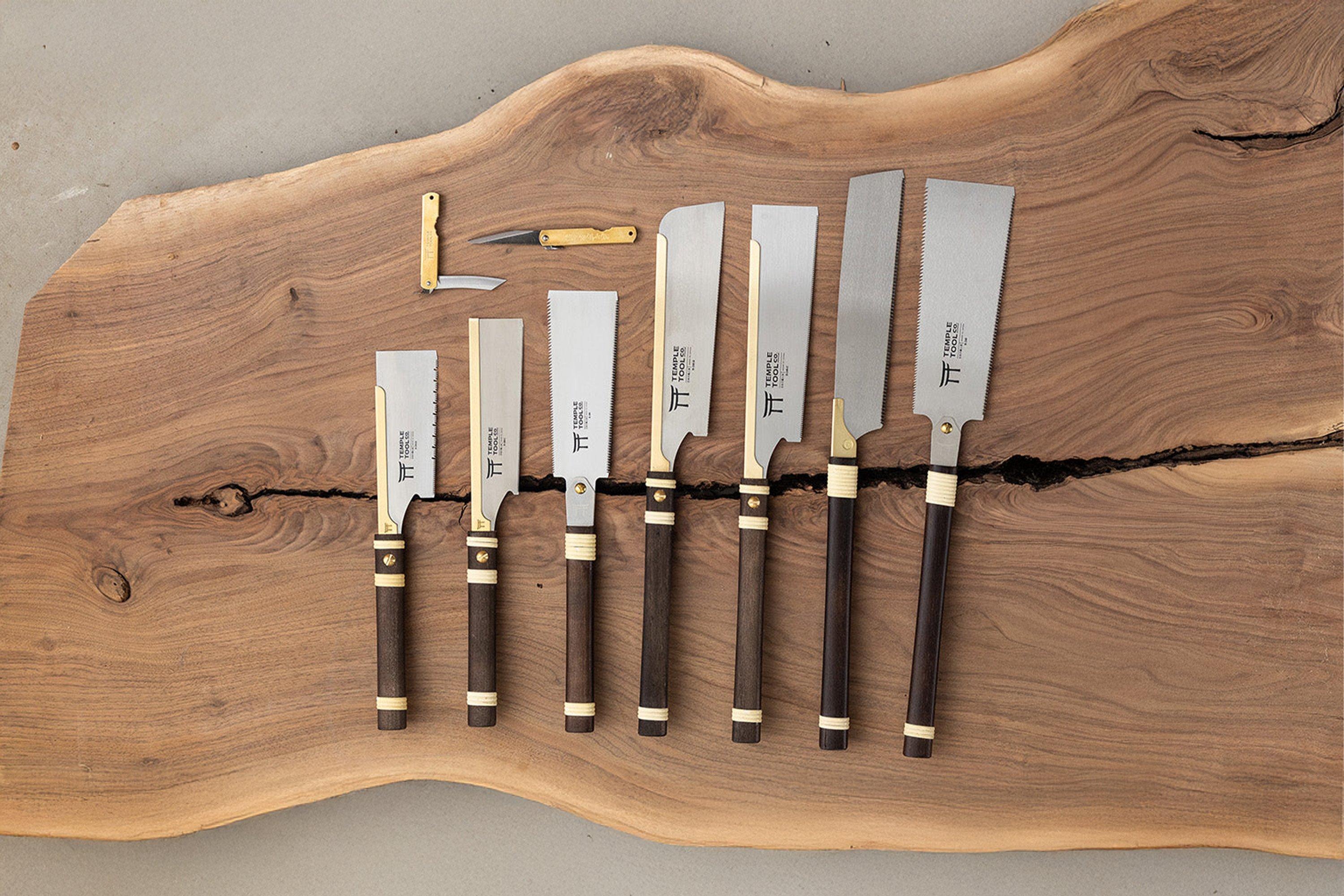 Temple Tool woodworking tools: several Japanese pull saws and two marking knives displayed on a live-edge wooden slab.