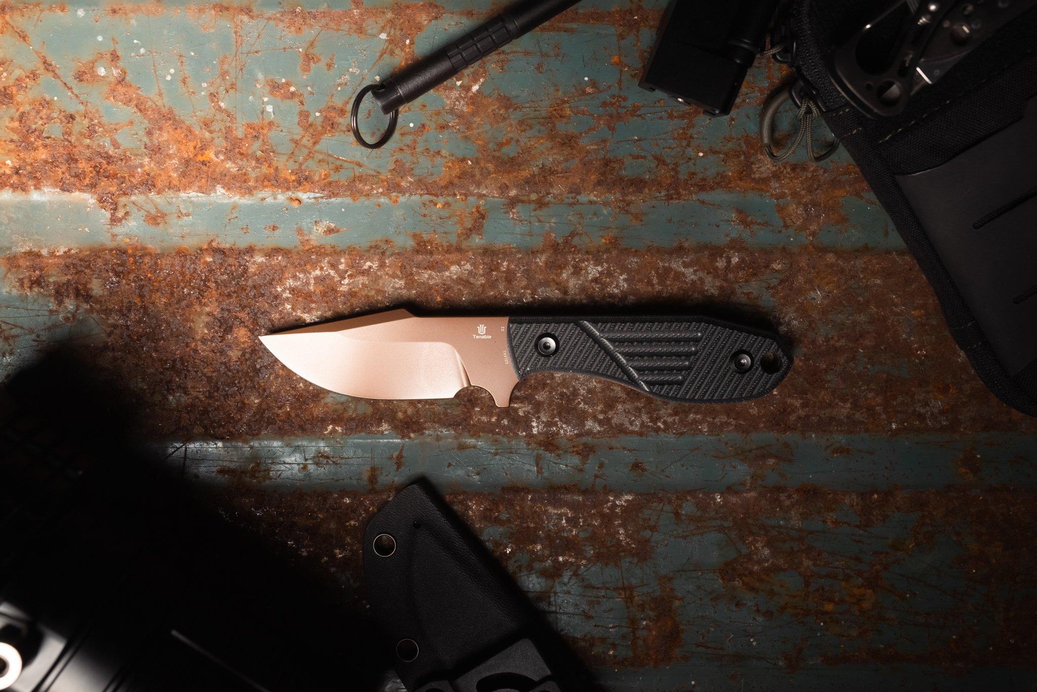 Un cuchillo fijo Tenable sobre un fondo de metal oxidado.