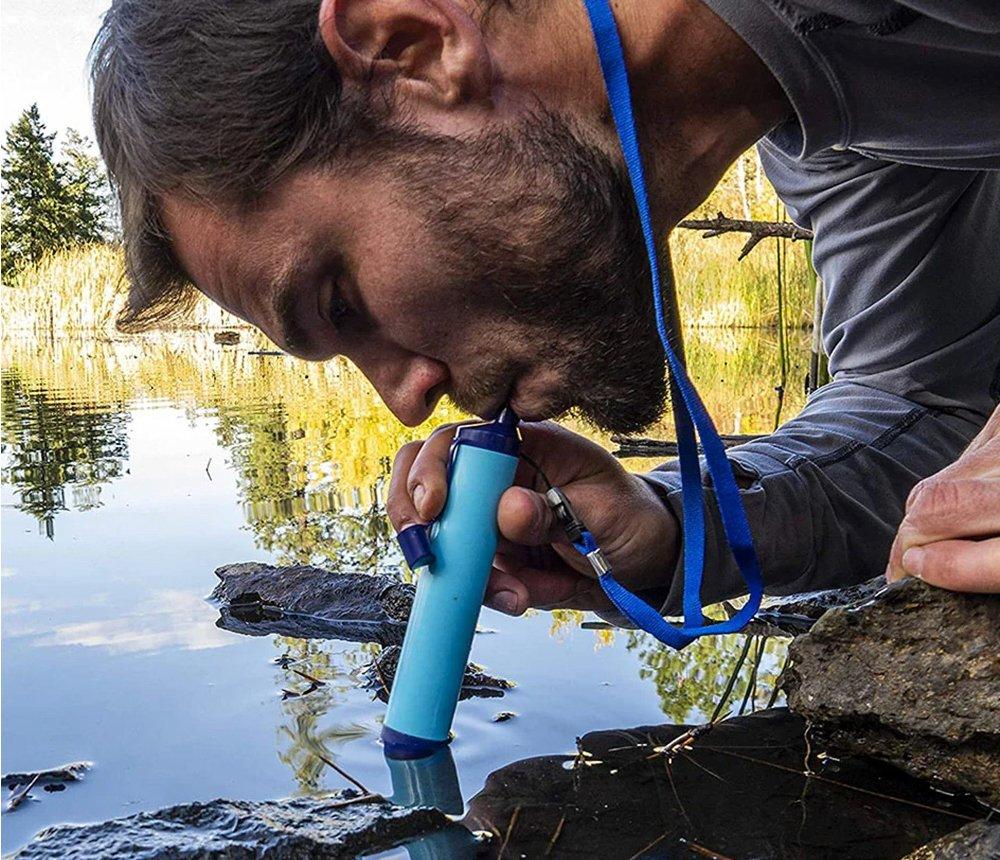 Een man drinkt met een waterfilter rechtstreeks uit een ven.
