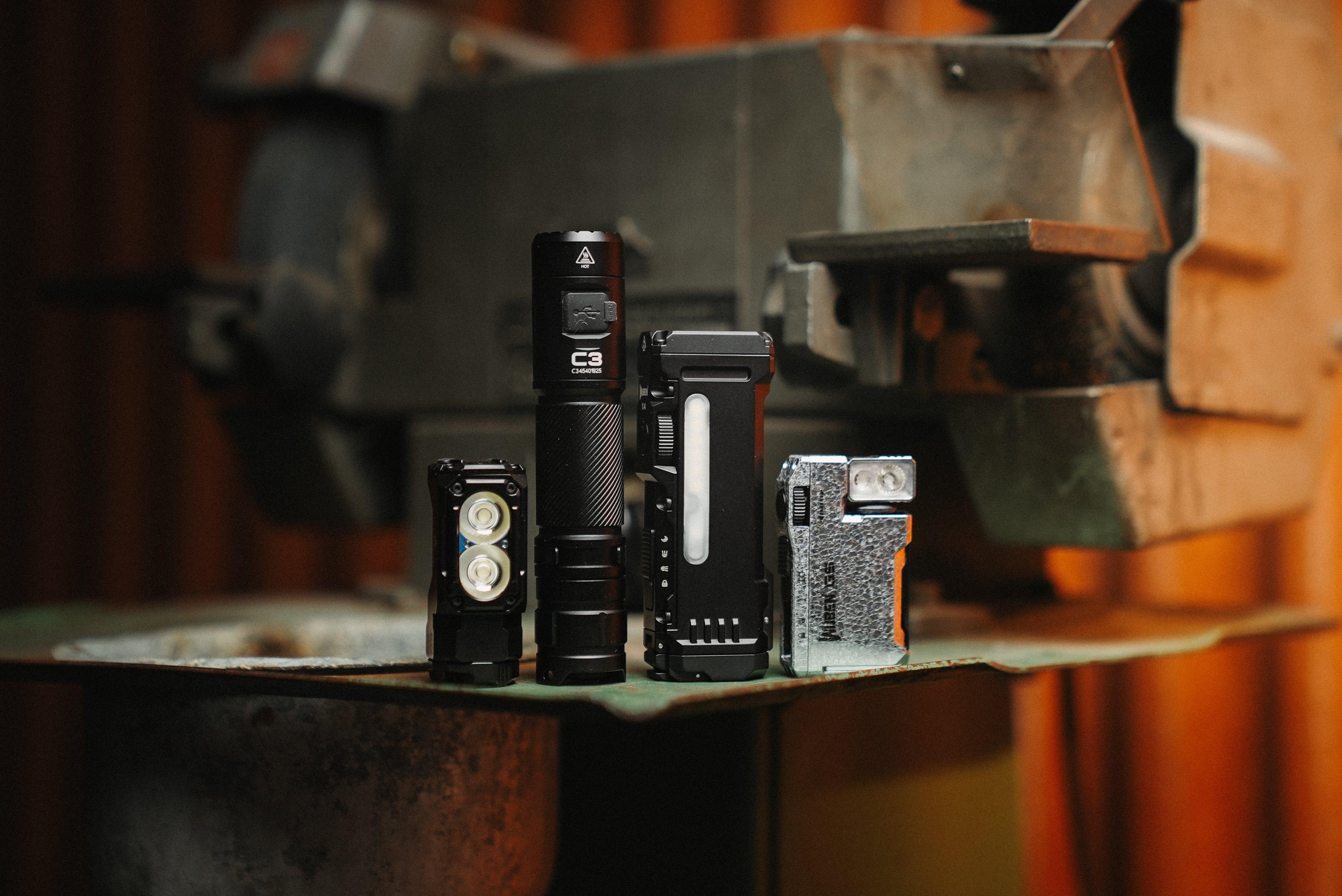 Four Wuben torches (E7, C3, X4 and G5) standing upright on a workbench in a workshop