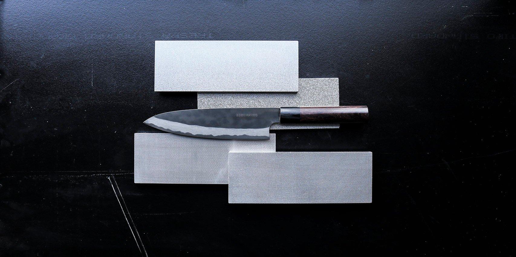 Un cuchillo de cocina sobre la mesa con varias piedras de afilar Atoma