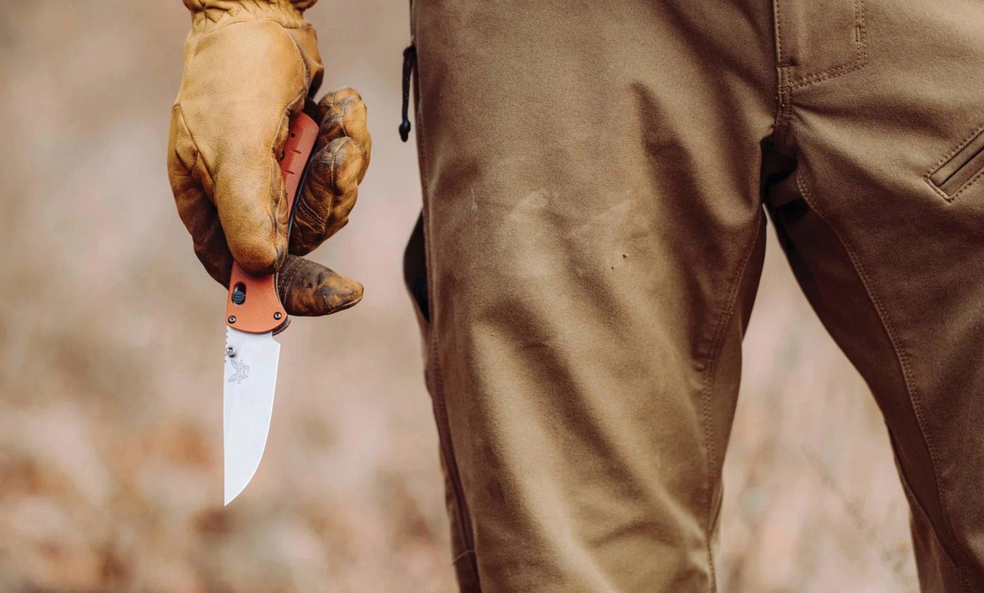 Benchmade SlipRidge-zakmes met oranje G10-handgreep, opengeklapt in een hand met werkhandschoen