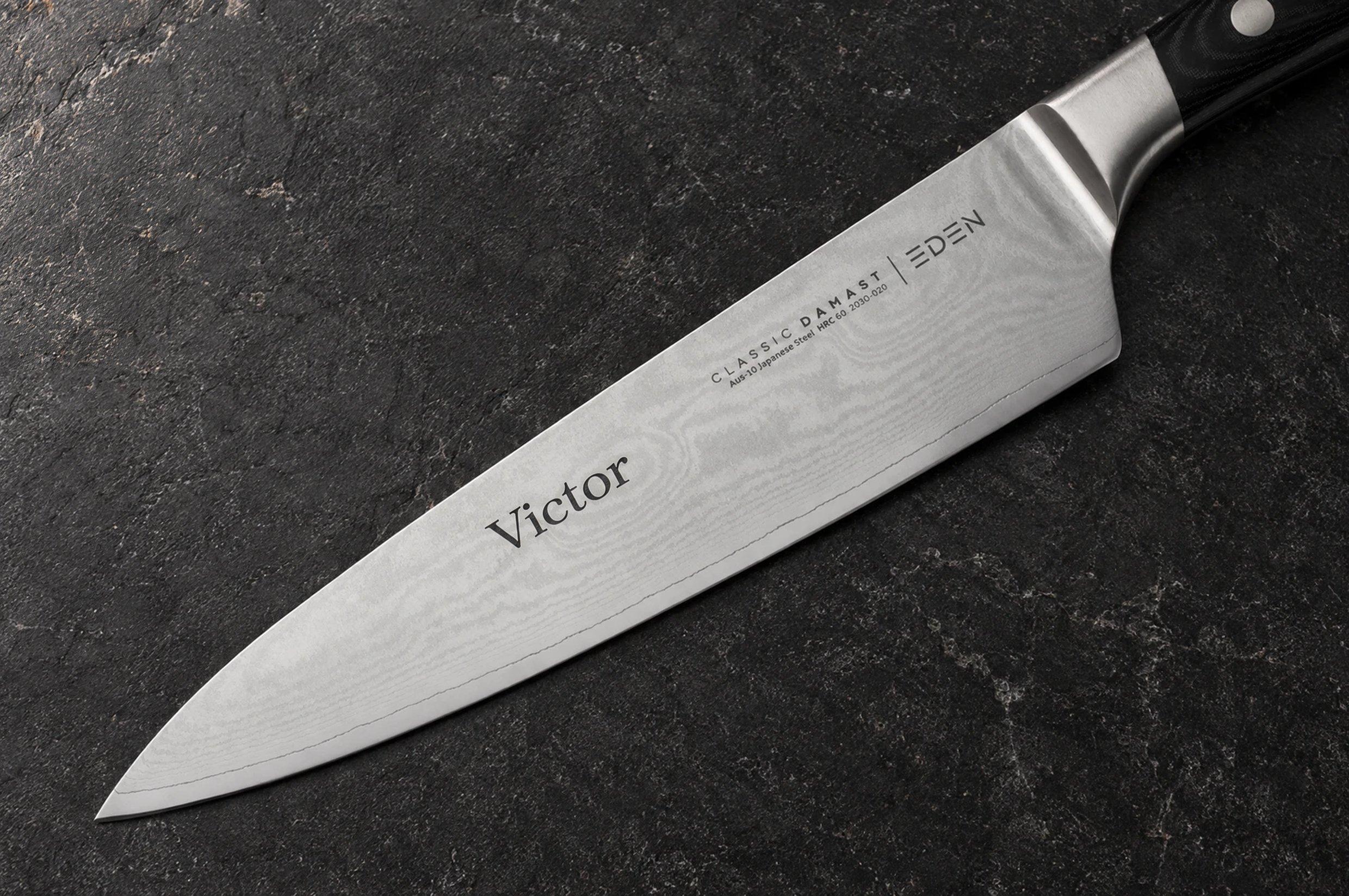 Eden-koksmes met damastlemmet en de gegraveerde naam “Victor”, op een donkere steen