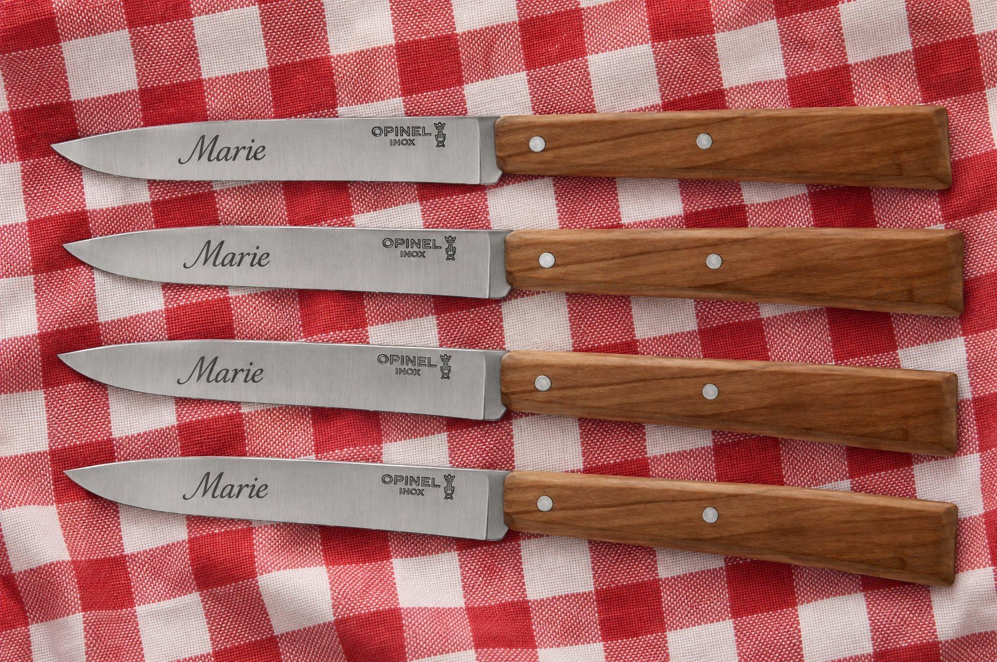 Vier Opinel-messen met houten heft en de gegraveerde naam “Marie”, op een rood-wit geruit tafelkleed