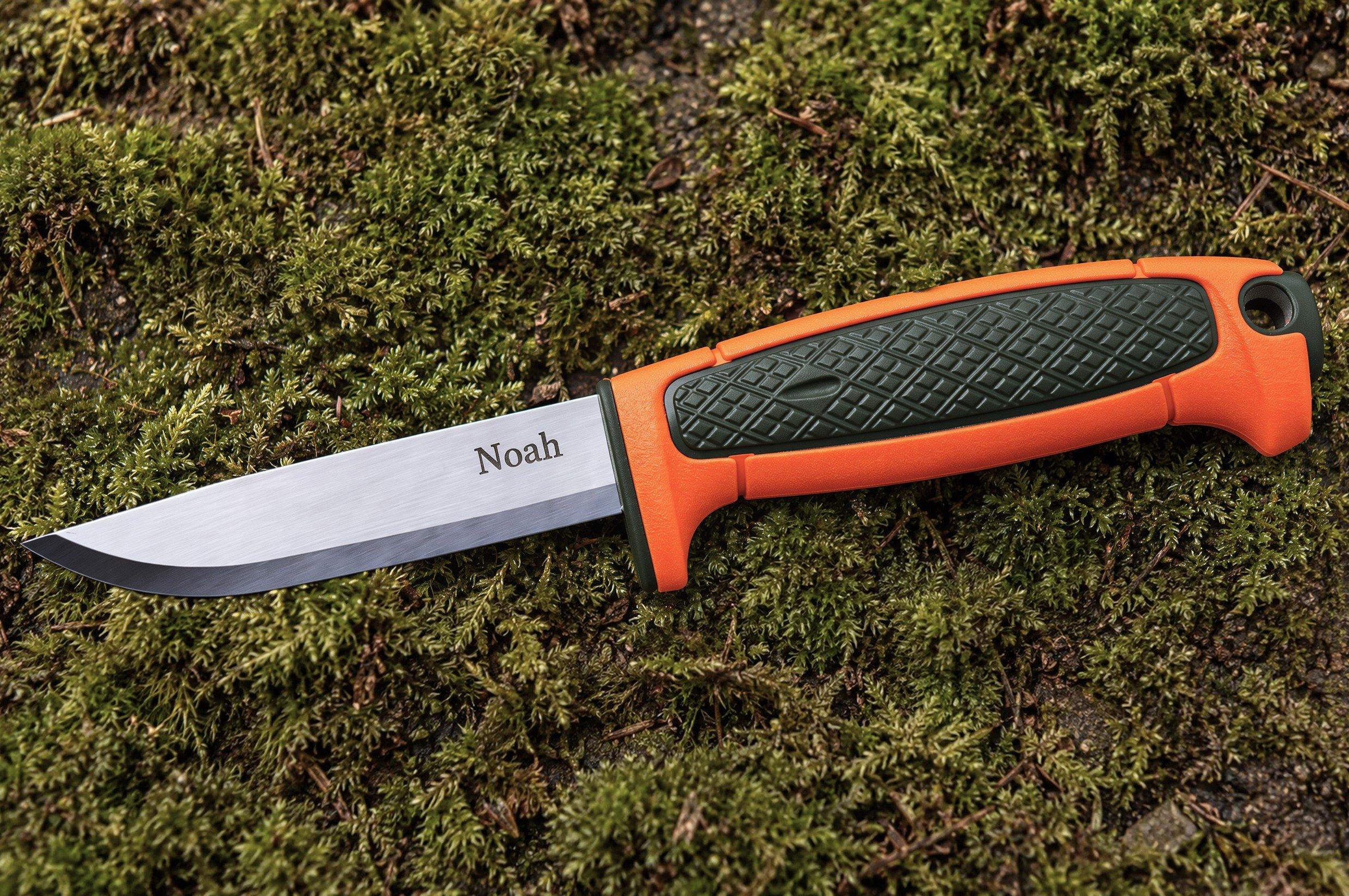 Vaststaand mes met oranje-groene handgreep en de naam “Noah” in het lemmet gegraveerd, op mos