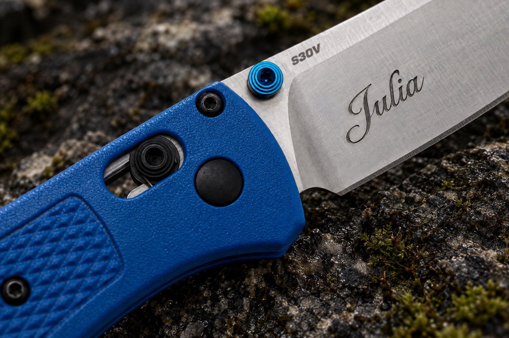 Blauw zakmes met de naam “Julia” in het lemmet gegraveerd, op een bemoste steen