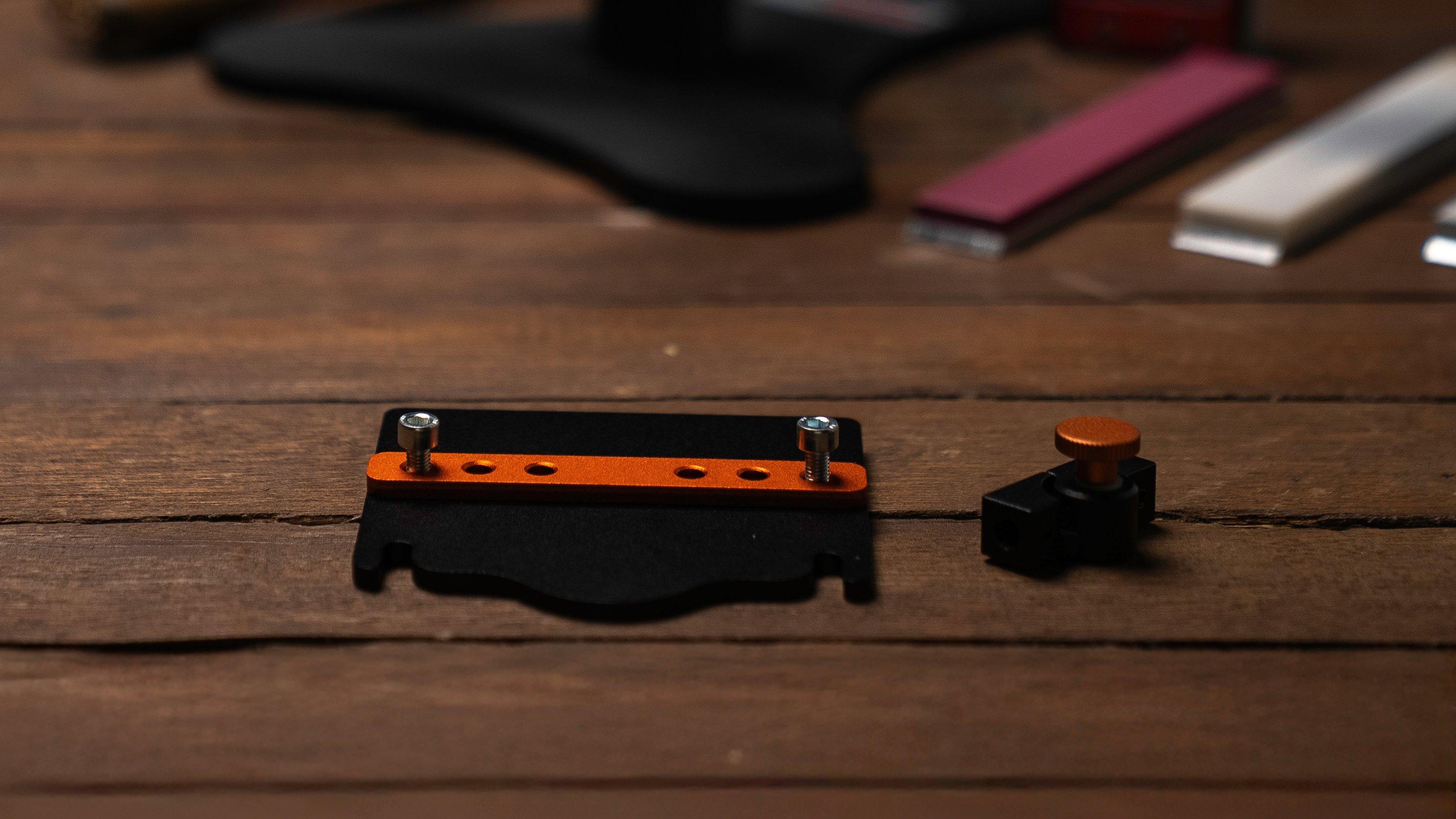 A Hapstone chisel and convex adapter on a wooden table with a Hapstone sharpening system and sharpening stones in the background