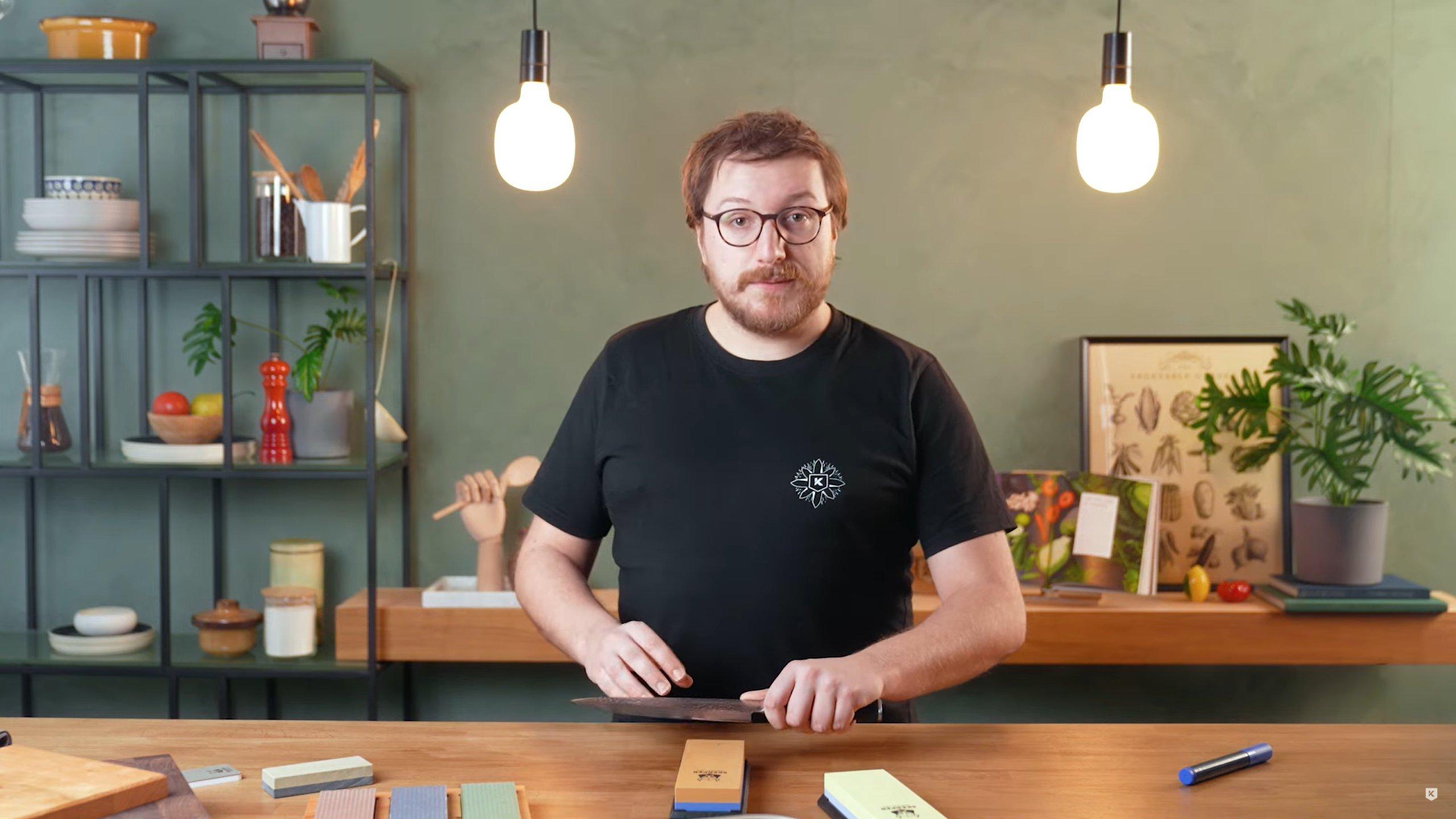 Una persona enseñando cómo afilar un cuchillo de cocina con una piedra de afilar sobre la mesa