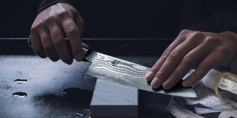 Una persona afilando un cuchillo con una piedra de afilar Kai Shun