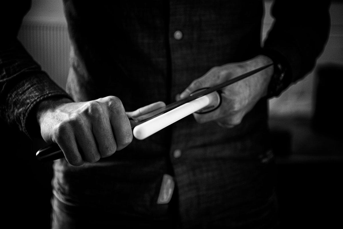 Schwarz-weißes Bild von jemandem, der ein Küchenmesser auf einem Wetzstahl schleift