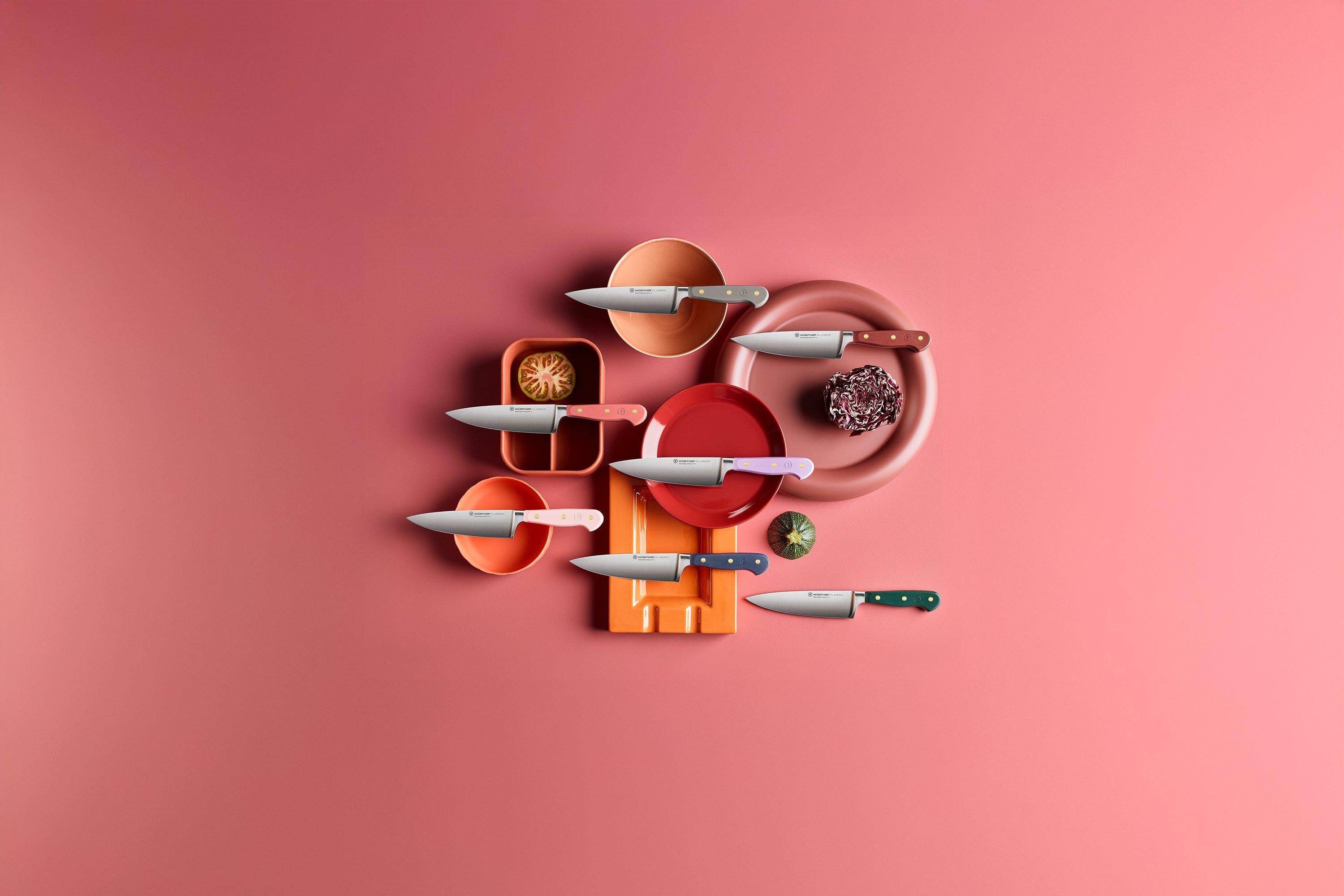 Meerdere Wüsthof Classic Colour keukenmessen in verschillende kleuren op een roze ondergrond